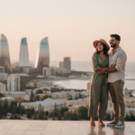 An Indian couple looking out at the futuristic Baku skyline and Caspian coastline during early evening golden hour.