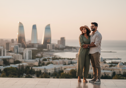 An Indian couple looking out at the futuristic Baku skyline and Caspian coastline during early evening golden hour.