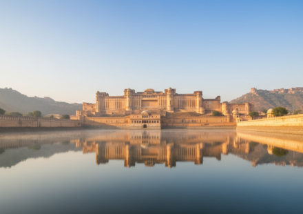 Amber Fort in Jaipur illuminated by warm morning sun, reflected in Maota Lake during clear autumn weather.