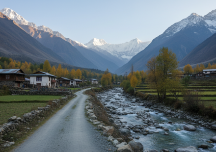 A quiet mountain road winding along a river toward snow-capped Himalayan peaks in a secluded valley.