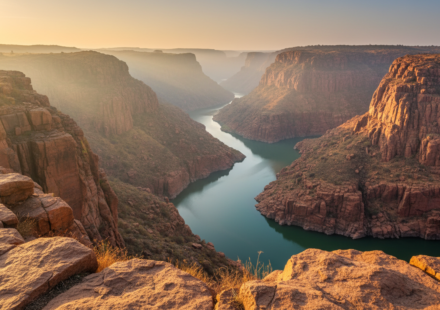 Dramatic red granite cliff face and winding river gorge in Gandikota under soft morning sunlight.