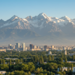 Almaty city skyline framed by high snow-capped mountains under a clear morning sky.