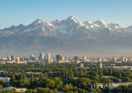 Almaty city skyline framed by high snow-capped mountains under a clear morning sky.