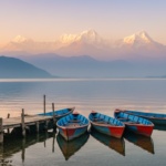 Colorful wooden boats resting on Phewa Lake in Pokhara with the snow-capped Annapurna mountain range in the background.