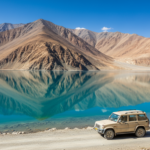 Clear turquoise lake surrounded by stark brown mountains under a bright blue summer sky in Ladakh.