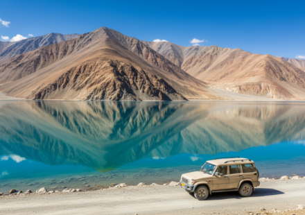 Clear turquoise lake surrounded by stark brown mountains under a bright blue summer sky in Ladakh.