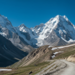 Winding high-altitude road through snowy mountain valleys in the Indian Himalayas under a clear blue sky.