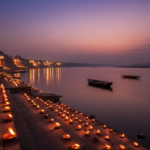 Thousands of glowing earthen lamps on stone riverbank steps lit at dusk beside a wide river.