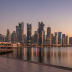 Dusk view of the Doha West Bay skyline reflected across the calm gulf water from the waterfront promenade.