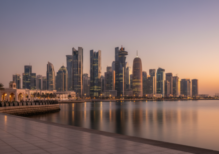 Dusk view of the Doha West Bay skyline reflected across the calm gulf water from the waterfront promenade.