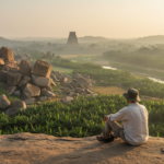 Sunrise view over Hampi boulder landscape with Virupaksha Temple tower in the distance.