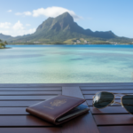 A wooden resort table overlooking a clear turquoise bay and green tropical mountain peak in Mauritius.